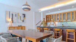 Una cocina moderna con barra de madera, sillas de mimbre y una mesa de comedor.