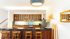 Una cocina moderna con armarios de madera, una isla central con taburetes, un microondas y un refrigerador.