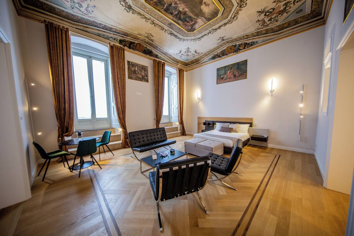 Ein Hotelzimmer mit Bett, Schreibtisch, Stuhl, Sofa und Esstisch.