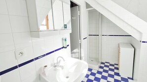 A bathroom with a white sink, mirror, and blue-tiled floor. - Hotel Restaurant L'Esperance (Saint-Cast-le-Guildo)