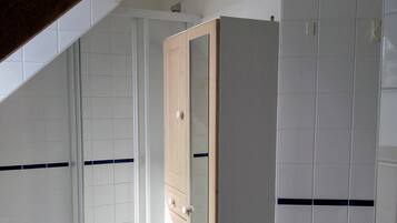 Une salle de bain avec des carreaux blancs, une porte en bois et un mur carrelé.