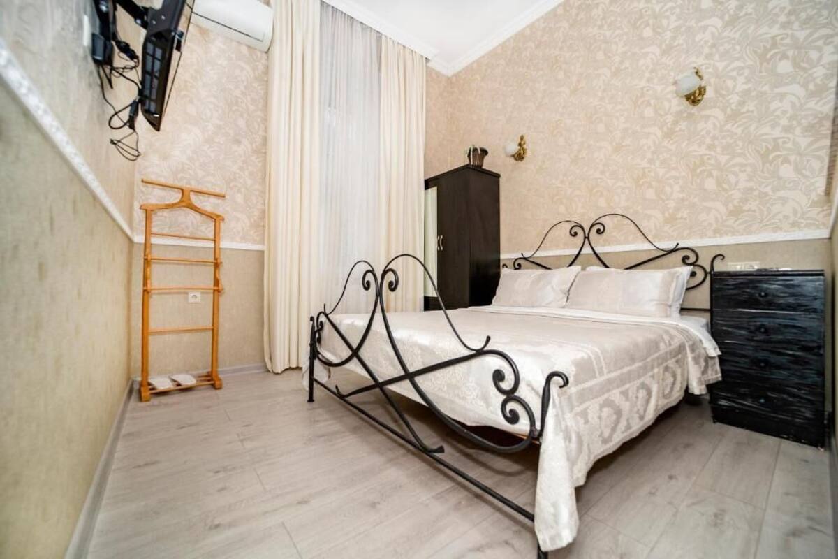 Un dormitorio con estructura de cama metálica, armario de madera, armario colgado y escalera de madera.