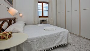 A bedroom with a bed, a bedside table, a lamp, a window with curtains, a wardrobe, and a painting on the wall. - Holiday Home in Tuscany Near Sassetta (Castagneto Carducci)