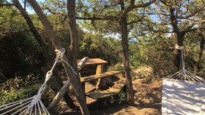 A hammock tied between trees, a wooden bench, and a white canopy structure in a forested area. - Holiday Home in Tuscany Near Sassetta (Castagneto Carducci)