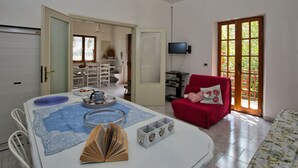 A spacious living room with a dining area, a red armchair, and a television mounted on the wall. - Holiday Home in Tuscany Near Sassetta (Castagneto Carducci)