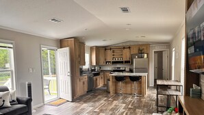Une cuisine moderne avec des meubles en bois, un réfrigérateur en acier inoxydable et un coin bar équipé de deux tabourets.