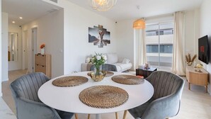 Un comedor moderno con una mesa redonda, sillas tapizadas en gris y posavasos tejidos.