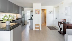 Uma cozinha moderna com armários cinzas, bancada de mármore e um banquinho de madeira.
