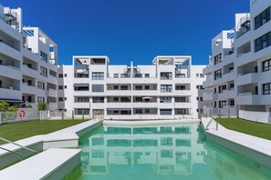 Un edificio moderno de varios pisos con una piscina al frente.