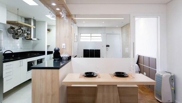 Une cuisine moderne dotée d’un îlot central, d’appareils électroménagers intégrés et d’un coin repas avec une table dressée pour deux personnes.
