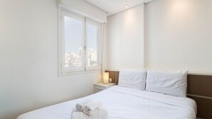 Une chambre d’hôtel avec un grand lit, une table de chevet avec une lampe et une fenêtre donnant sur la ville.