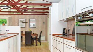 Eine moderne Küche mit Holzboden, weißen Schränken und einem Essbereich mit Tisch und Stühlen.