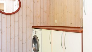 Ein kleiner Hauswirtschaftsraum mit Waschmaschine, Schränken und einem Spiegel.