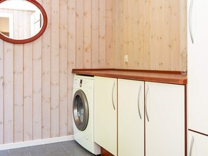 A compact laundry room with a washing machine, cabinets, and a mirror. - 4 Person Holiday Home in Glesborg (Glesborg)