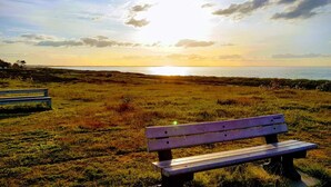 A bench in a grassy field with a sunset in the background. - 4 Person Holiday Home in Glesborg (Glesborg)