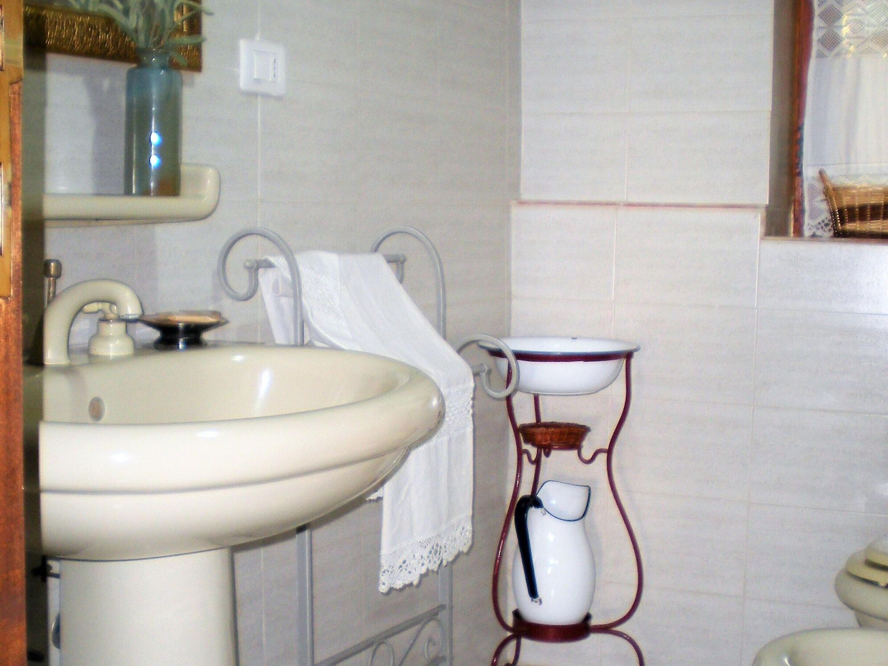 Un baño con lavabo, espejo, toallero y retrete.