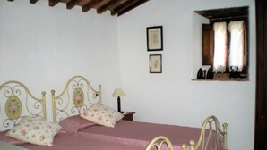 A bedroom with a bed, pillows, a nightstand, a lamp, and a window with curtains. - Farmhouse in Cortona With Pool (Cortona)