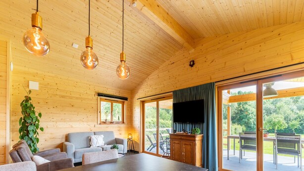 Een houten interieur met een eettafel, banken en een televisie.