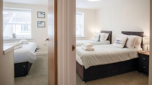 Une chambre d’hôtel avec deux lits, un bureau et une fenêtre avec des stores.