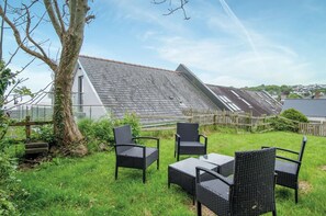 A patio with outdoor furniture, a tree, and a house with a sloped roof. - Dolphin - 2 Bedroom Apartment - Saundersfoot (Saundersfoot)