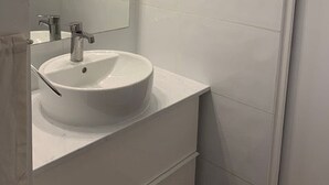 Een badkamer met een witte wastafel, spiegel en betegelde wanden.
