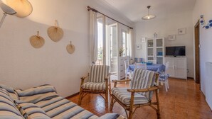 Un salon avec des canapés à rayures, des fauteuils en osier, une table à manger et un téléviseur.