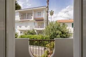 A white building with balconies, a palm tree, and a clear sky. - Quiet Apartment by Wonderful Italy (Sanremo)