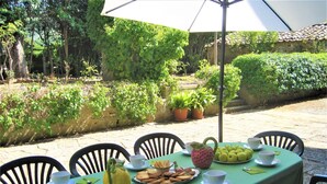 An outdoor dining table with chairs, plates of lemons, a pitcher, and a bowl of cookies.