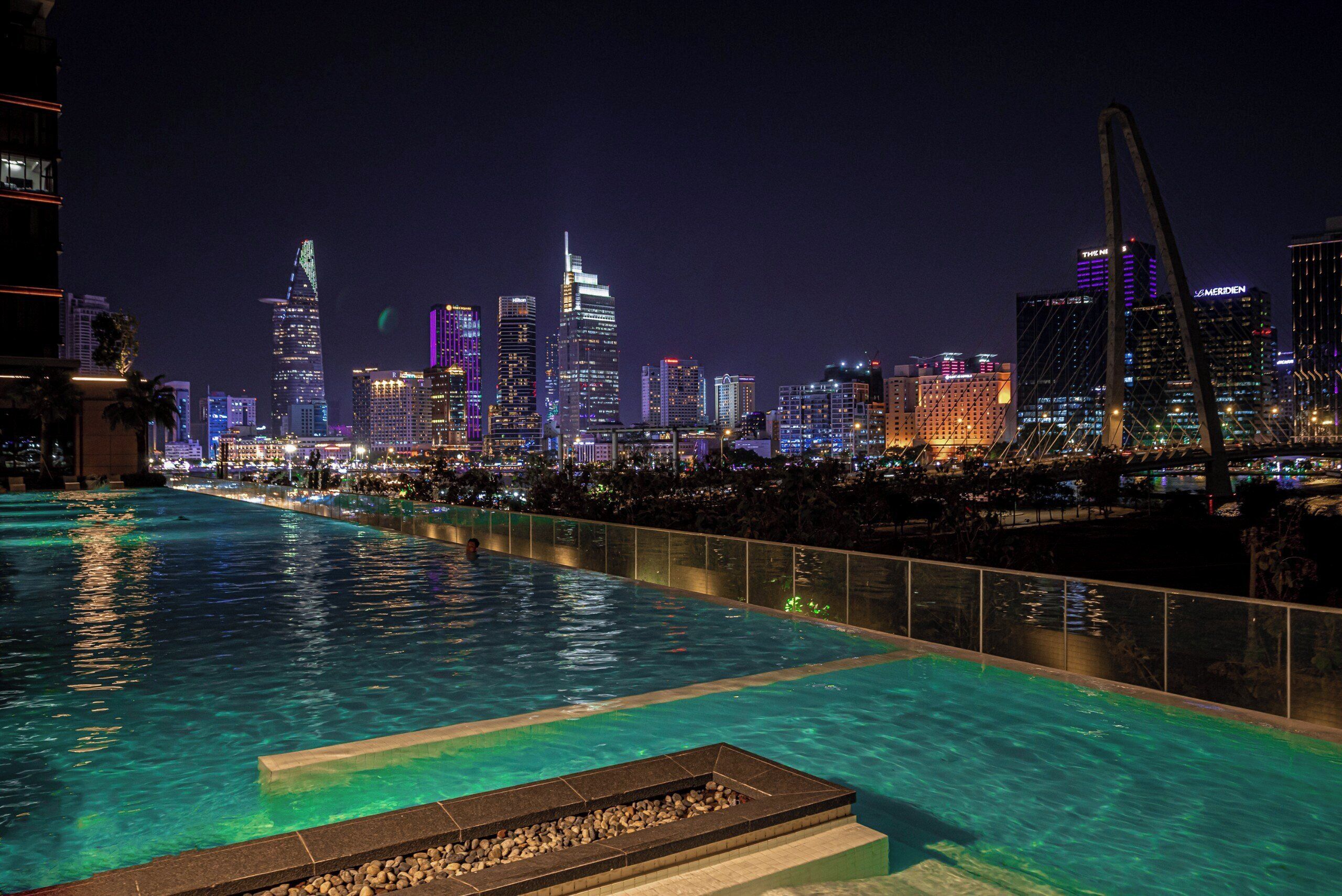 A nighttime cityscape with a pool area.