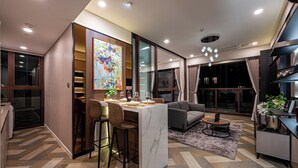 A modern living room with a dining area, a sofa, and a coffee table. - Metropole Apartment Thu Thiem (Ho Chi Minh City)