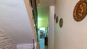 A staircase with a brick wall on one side and a tiled floor. There are decorative plates on the wall and a door leading to another room. - Belvilla by OYO Casa Romano (Polino)