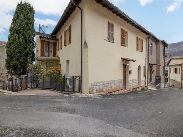 A two-story building with a stone foundation, wooden shutters, and a tiled roof.