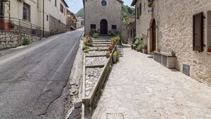 A narrow street leading to a stone building with a bell tower, surrounded by traditional architecture and stone walls. - Belvilla by OYO Casa Romano (Polino)