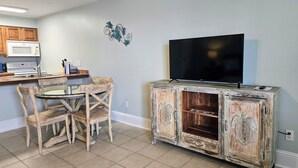 A kitchen with a dining table and chairs, a TV on a wooden cabinet, and a microwave above the stove. - SB#3: Dog Friendly, Across from the Beach, Free Daily Activities! (Pensacola)