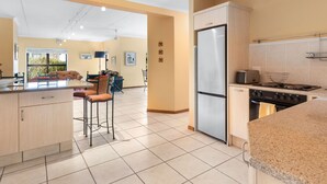 A modern kitchen with a refrigerator, stove, and bar stools.
