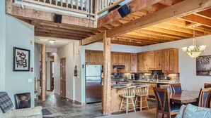 A spacious kitchen with wooden cabinets, a central island with bar stools, and a dining table. - Snowy Creek by Okanagan Premier (Beaverdell)