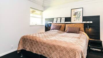 A bedroom with a bed, a window, a headboard, and wall art.
