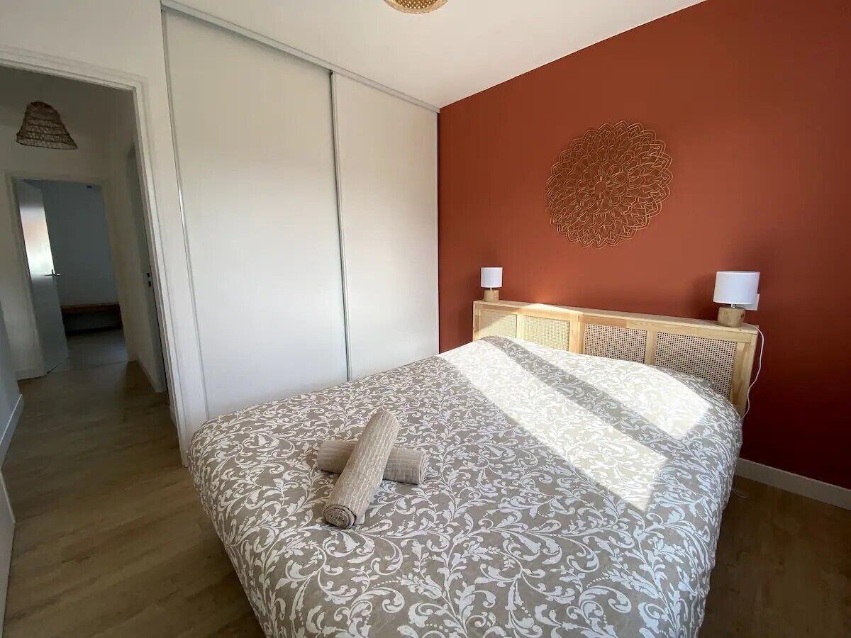 A bedroom with a bed, a wooden headboard, and a decorative wall piece.