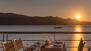 A table set for dining with a view of a sunset over water and mountains in the background. - Northern Lights Modern Retreat (Steinberg)