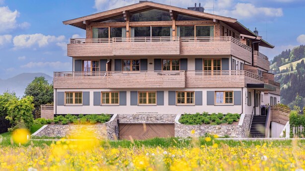 Un immeuble en bois à plusieurs étages, doté de balcons, qui se dresse sur un fond de paysage montagneux.