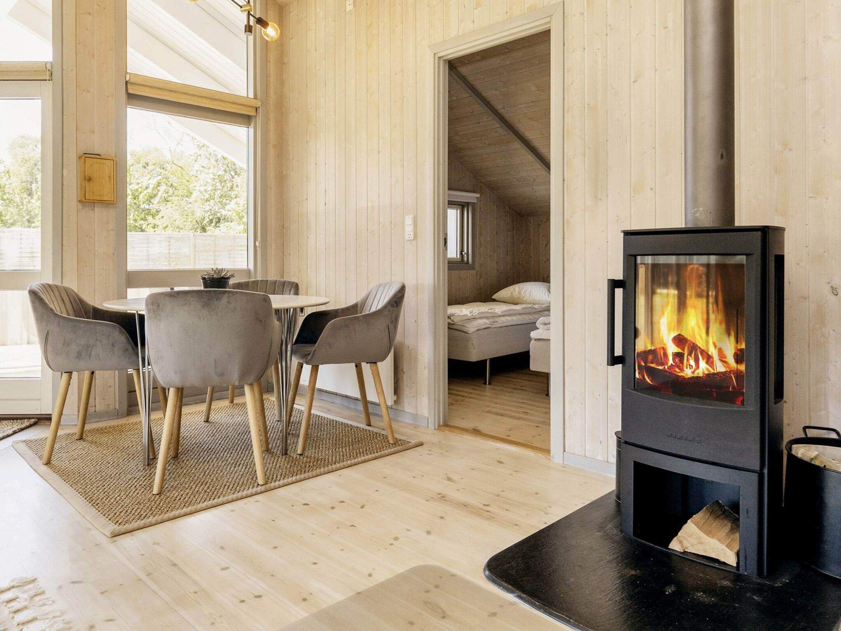A cozy room with a wood-burning stove, a dining area with chairs, and a bed.