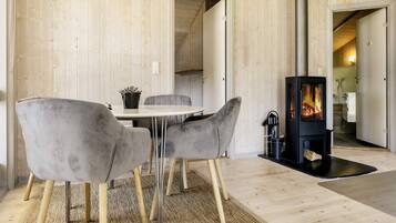 Een modern interieur met een houten wand, een ronde tafel met stoelen, een open haard en een klok.