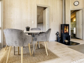 A modern interior with a wooden wall, a round table with chairs, a fireplace, and a clock. - 4 Star Holiday Home in Praesto (Praesto)