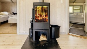A modern room with a wood-burning stove, a bed, and a bathtub. - 4 Star Holiday Home in Praesto (Praesto)