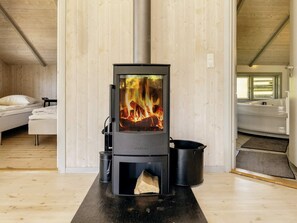 A modern room with a wood-burning stove, a bed, and a bathtub. - 4 Star Holiday Home in Praesto (Praesto)