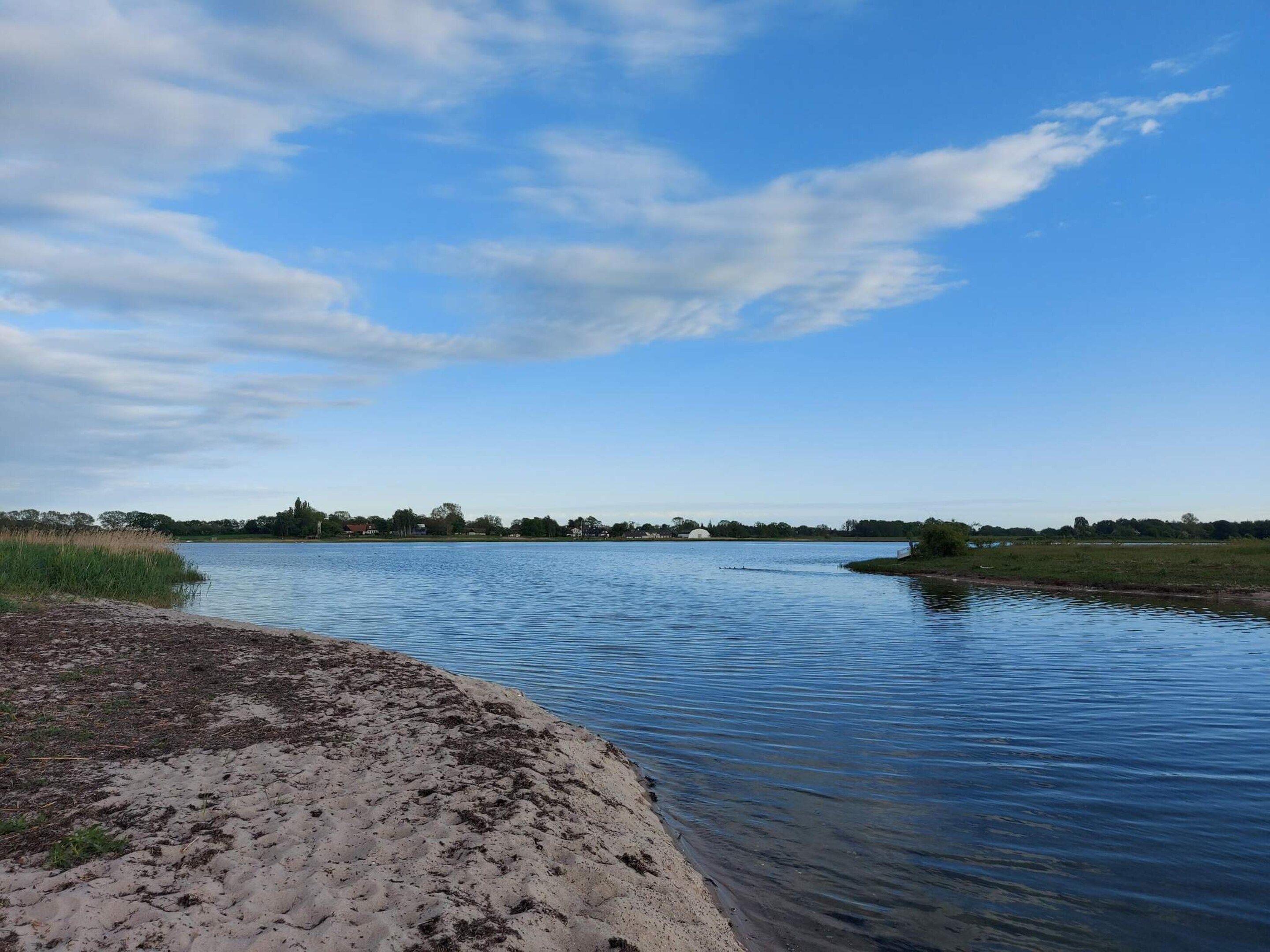 Une rivière paisible, avec des berges sablonneuses et un ciel dégagé.