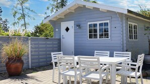 A small, single-story building with a white exterior and a door with a diamond-shaped window. - 4 Star Holiday Home in Praesto (Praesto)
