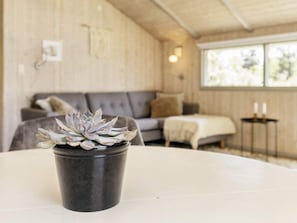 A room with a round table, a grey sofa, and a window with natural light. - 4 Star Holiday Home in Praesto (Praesto)