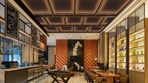 A modern bar area with a foosball table, bar counter, and shelves of bottles.