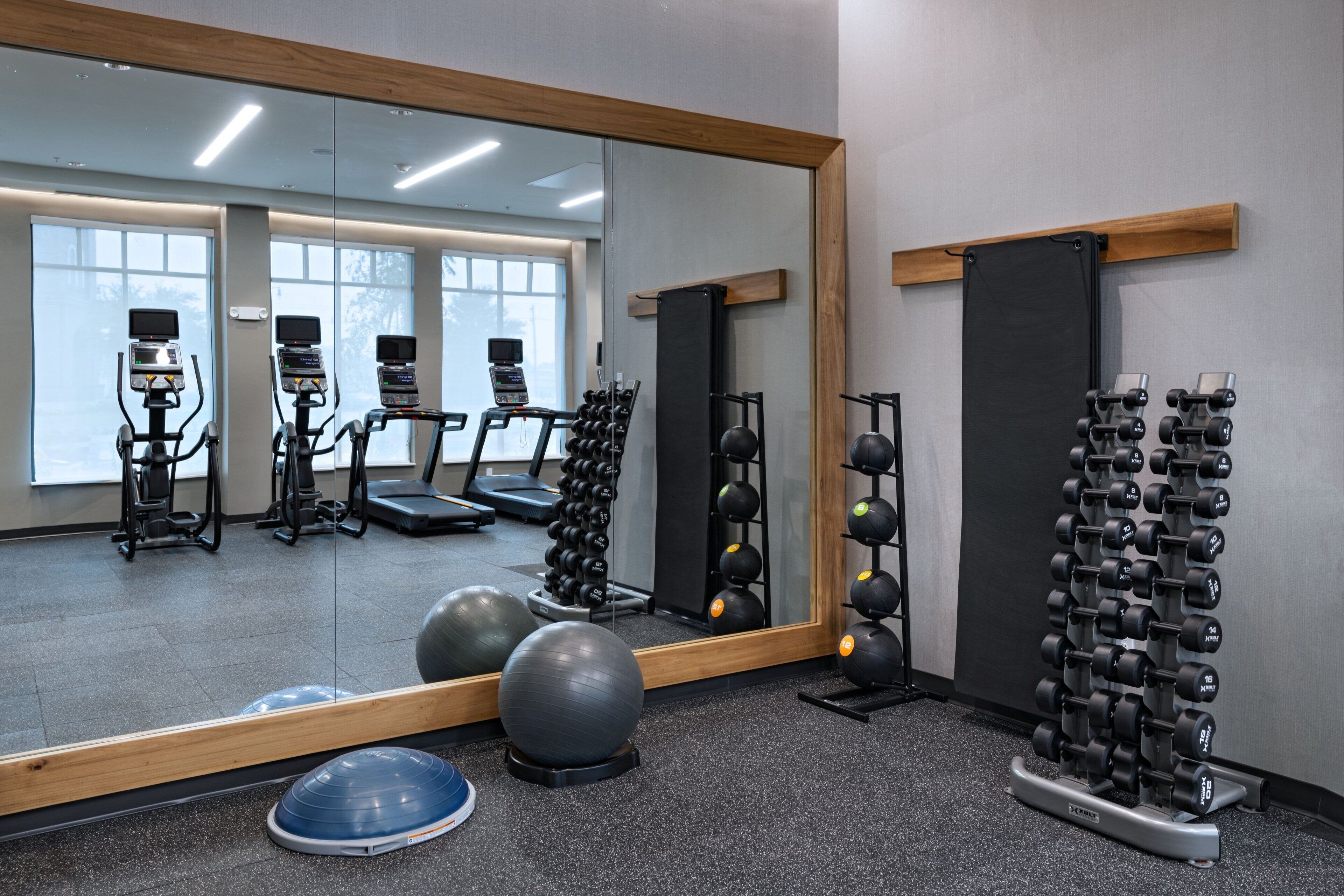 Un gimnasio con equipo de ejercicio, un espejo y una ventana.